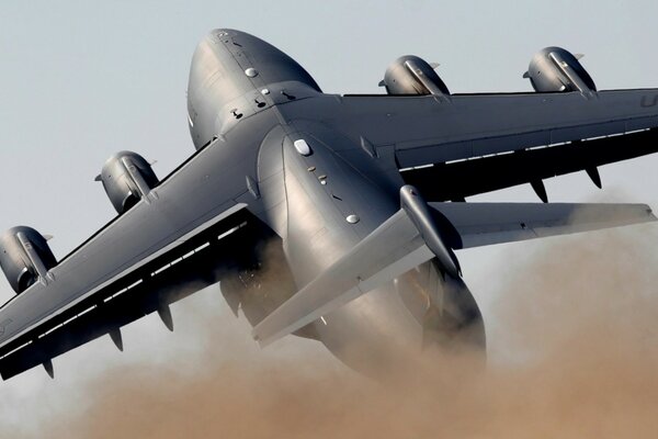 The flying gray Boeing has a smoky tail