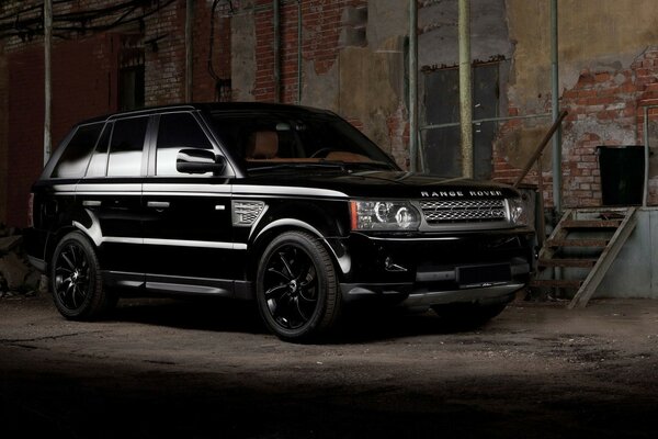 A black Land rover SUV at a dilapidated building