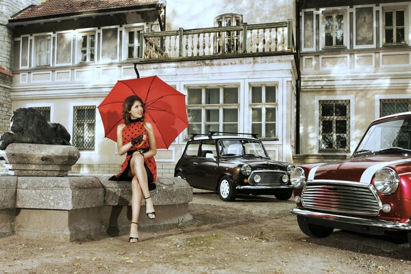 Bruna con ombrello in abito rosso e auto retrò