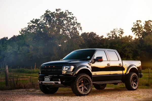 Black Ford pickup truck on a dirt road