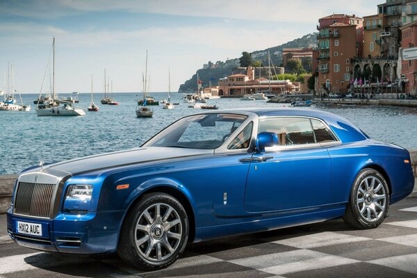 Coche azul frente a los barcos y el mar