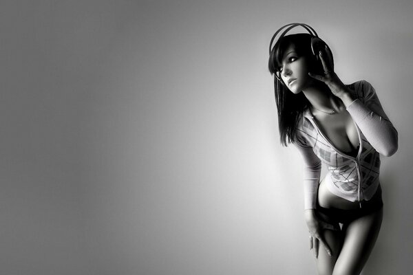 The girl at the wall. Wearing headphones. Gray photo