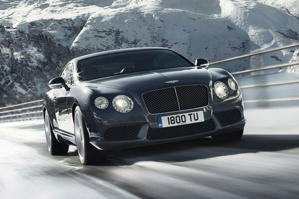 Bentley supersports on the road against the background of snow-covered rocks