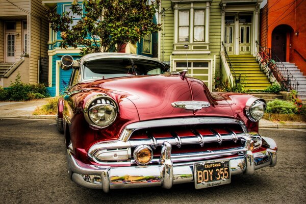 Retro kirschfarbenes Auto in der Nähe von Häusern professionelles Foto