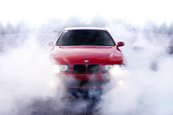 Voiture rouge avec les phares allumés en fumée