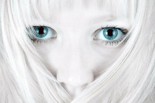 The face of a girl with white hair and blue eyes