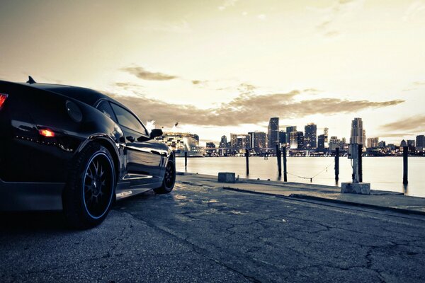 A black car is parked on the city embankment