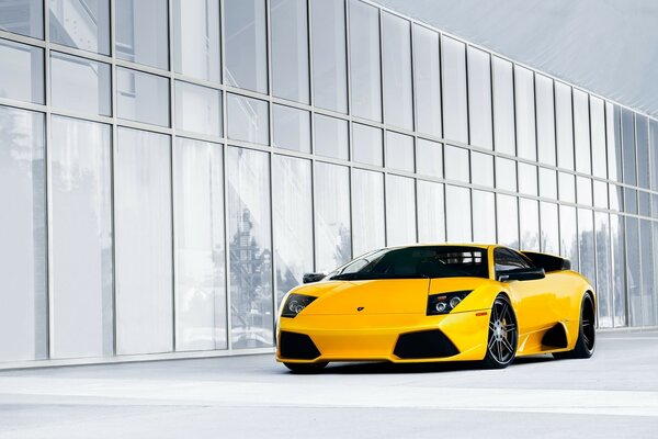 Yellow Lambirghini near the glass building