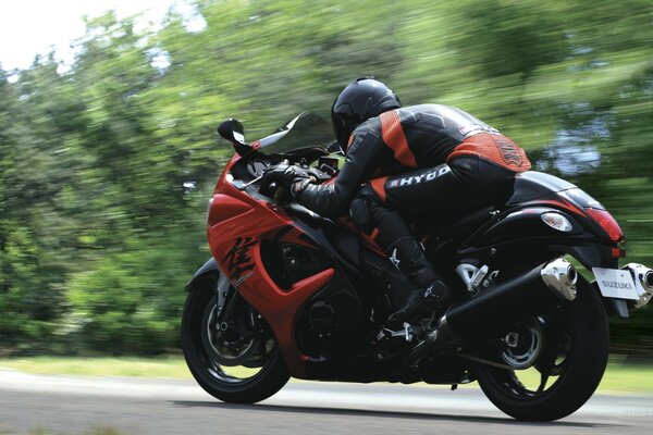 Moto de sport avec chauffeur à la vitesse sur fond de forêt