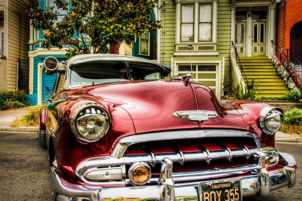 Vintage car burgundy color on the background of the house street