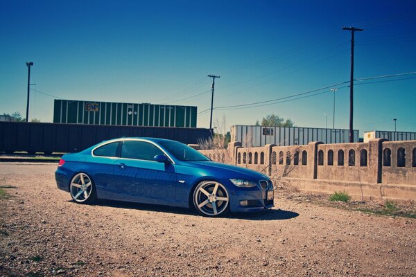 Blue BMW next to train and fence