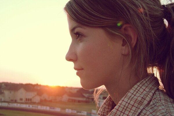 A girl in profile against a sunset background