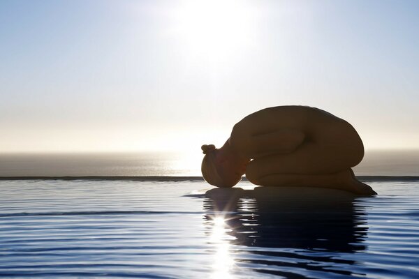 A girl does yoga by the water