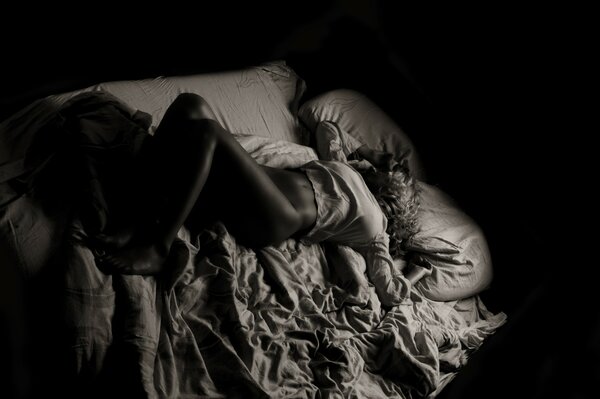 Black and white photo of a girl on the sheets