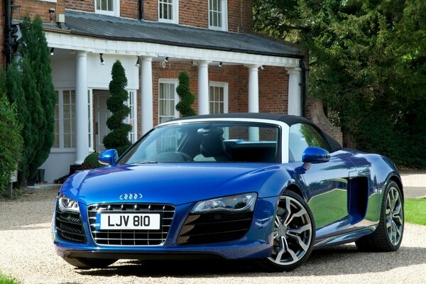 Audi R8 Spyder blu sullo sfondo del cortile della casa