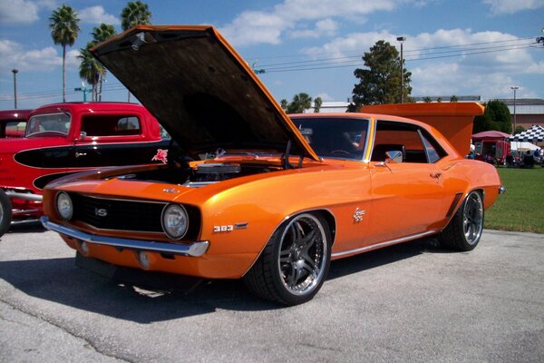 Orange classic car with open hood and trunk