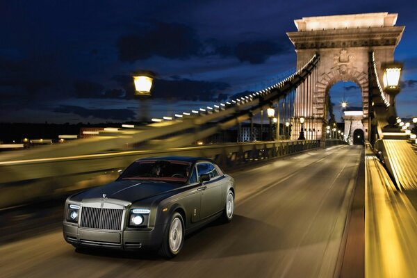 Gris mate Rolls Royce corre por el puente por la noche