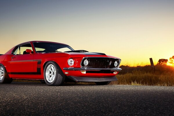 Supercar rouge mustang boss 302 conduit au coucher du soleil