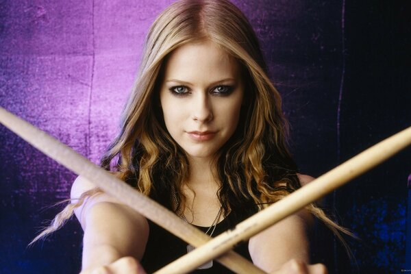 Singer Avril Lavigne with a crossed wooden weapon