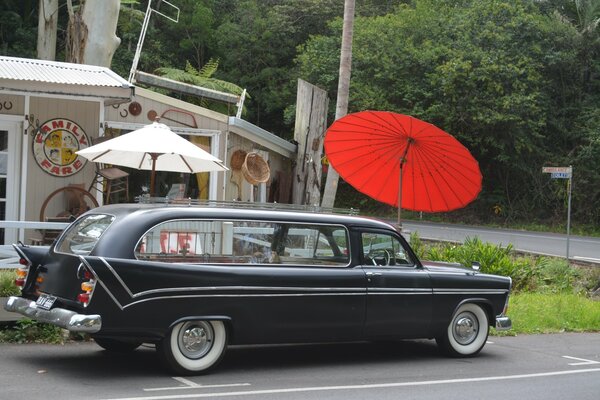 A long retro car at the red umbrella