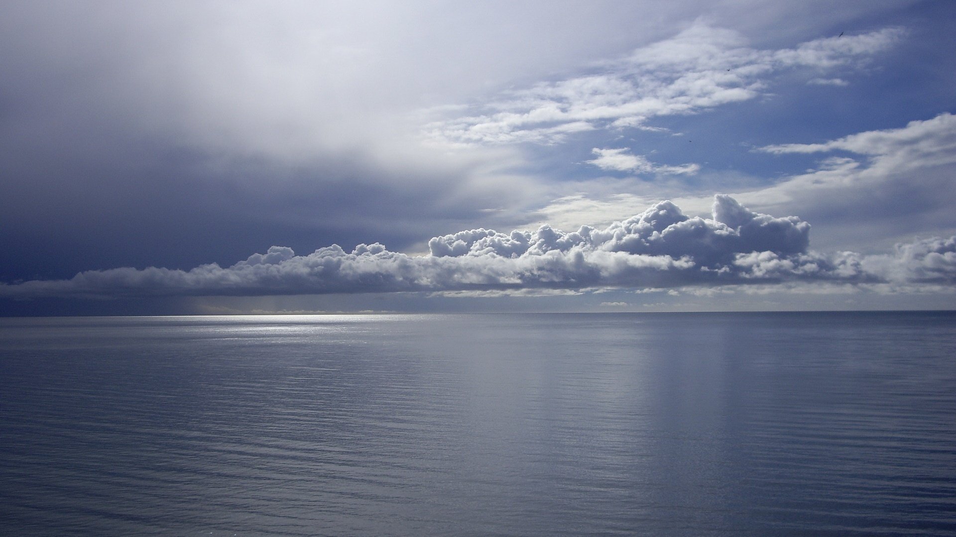 cielo azul oscuro resplandor en el agua rayos de luz cielo agua superficie horizonte paisaje mar calma silencio nubes