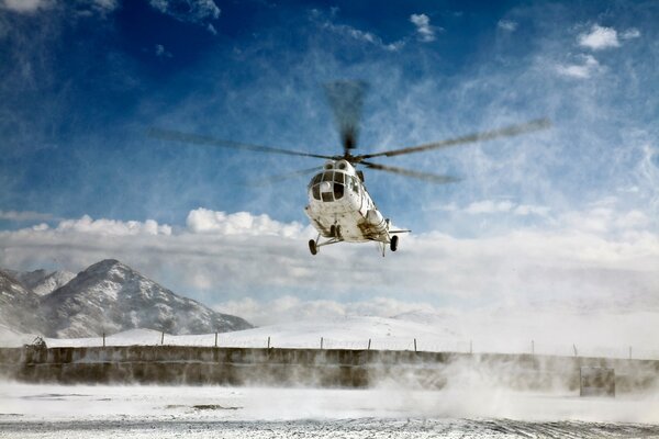 Mi-8 helicopter takes off against the backdrop of snowy mountains