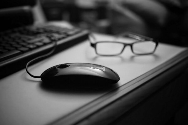 Glasses and computer keyboard mouse on the table