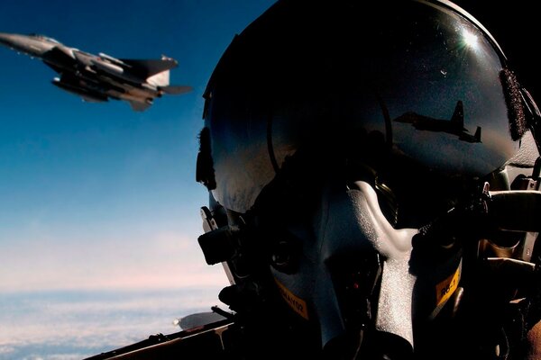 A fighter pilot wearing a helmet on the background of a flying plane