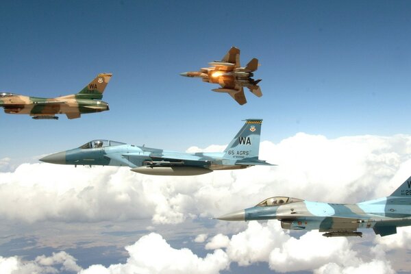 Four planes flying above the clouds in the blue sky