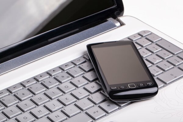 A smartphone lying on a laptop keyboard