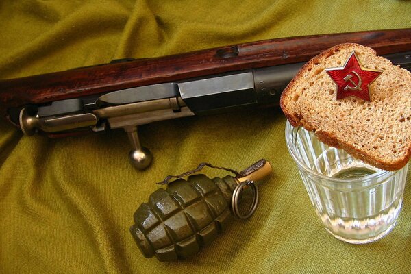 Eine Maschine, eine Granate, ein Glas Wodka und Brot auf einem Tuch