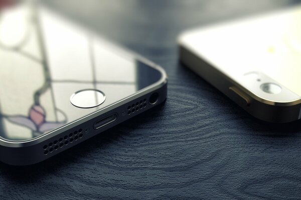 Two black iPhones on a black wooden surface