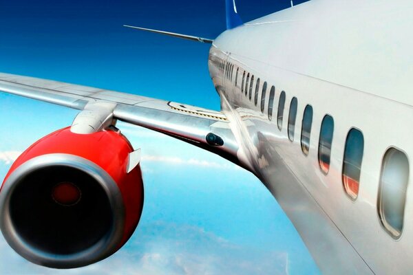 The passenger is comfortable in such an airplane to fly with a view of the red turbine in the blue sky