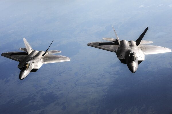 Two f - 22 raptor fighters are flying on a mission