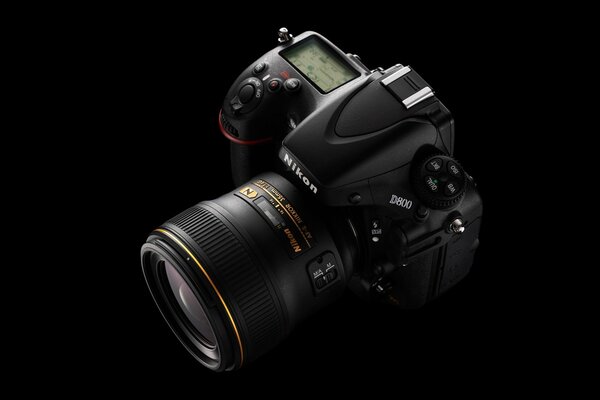 On a black background - a professional nikon camera with a powerful lens