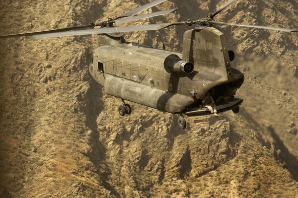 Helicóptero Chinook volando en el fondo de las montañas