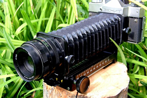 The lens of the Zenith camera accordion on a stump against the background of grass