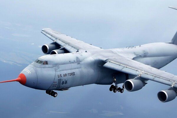 A modern plane with a red nose flies through the sky