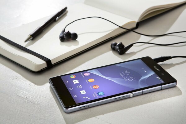 Smartphone sony avec casque, stylo et bloc-notes