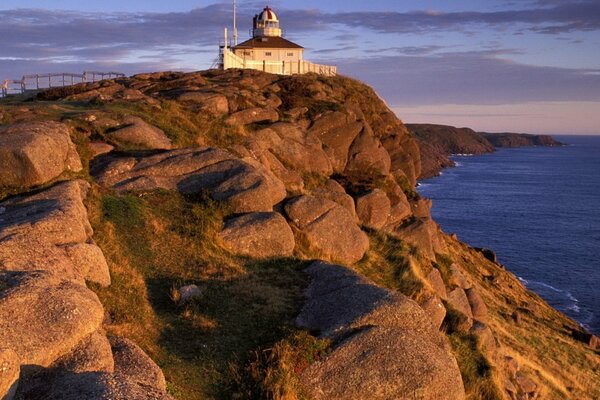 Lighthouse on a ledge in the sea at sunset