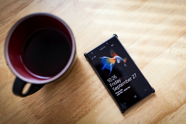 Teléfono de Nokia y taza de café en la mesa de madera