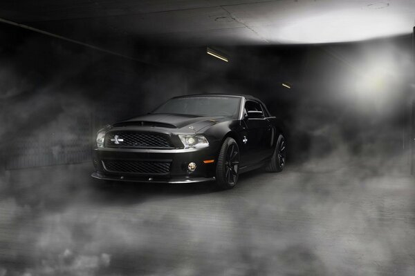 Voiture noire Ford Mustang coupe la route dans le brouillard