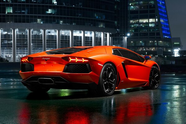 Lamborghini aventador naranja en el fondo de la ciudad nocturna