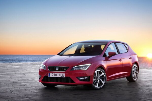 Hermoso coche rojo en el fondo de la puesta de sol