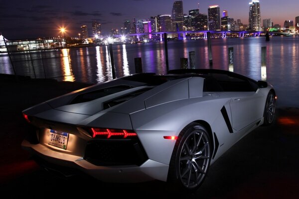 Coche en la noche junto al río en el fondo de la ciudad