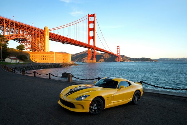 Voiture au bord de la côte avec pont au coucher du soleil