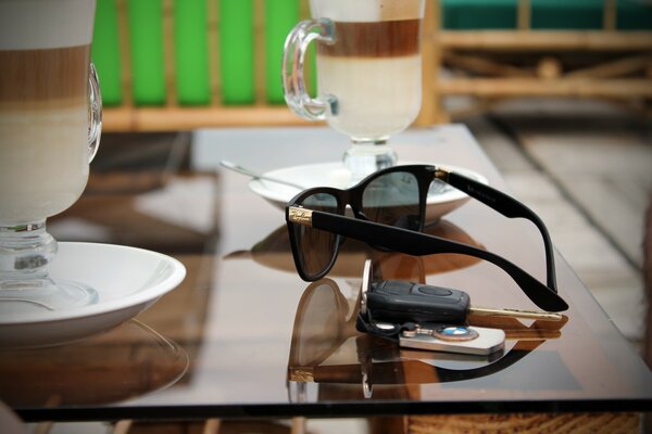 Table sur laquelle se trouvent des tasses, des lunettes et des clés avec un porte-clés BMW