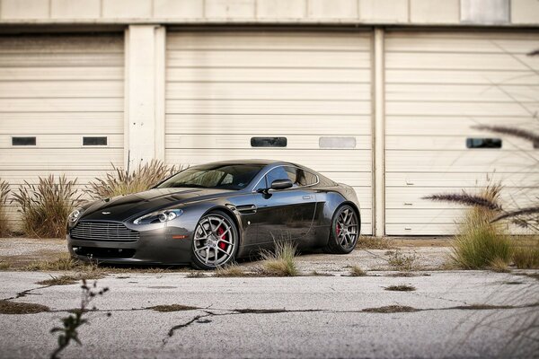 Auto Aston Martin grigio scuro su uno sfondo di garage chiusi