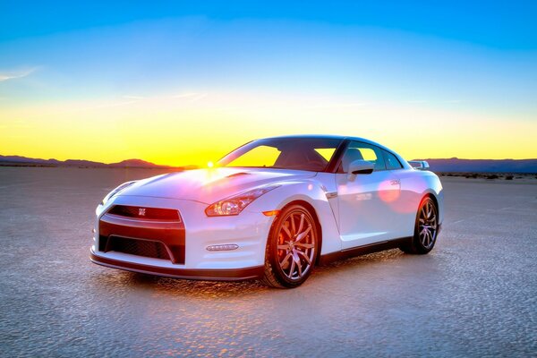 Белый nissan gt-r на фоне закатного неба