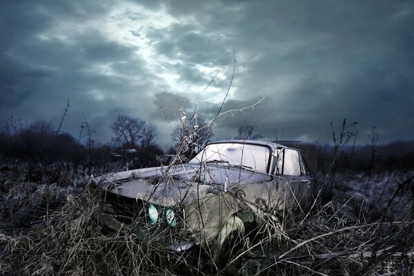 An old car with its headlights on in nature